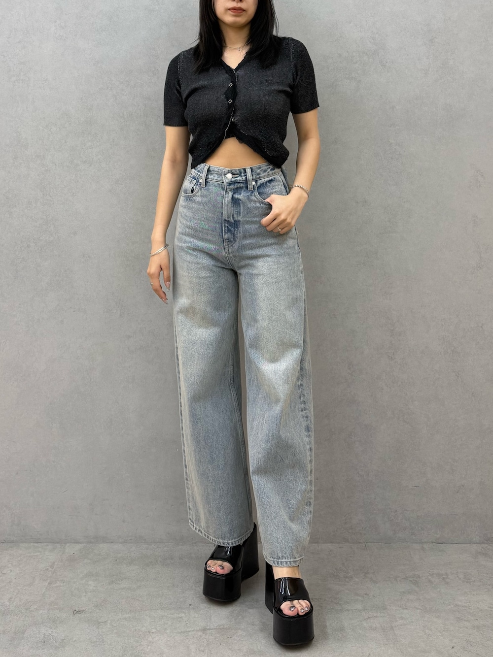 ブラック系のニット/セーター、ブルー系のデニムパンツ、ブラック系のサンダルを着用したレディースの春コーディネートの1枚目の写真