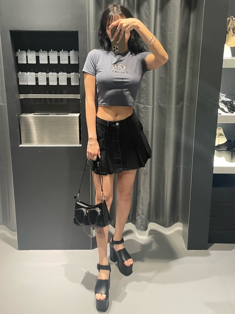 グレー系のTシャツ/カットソー、ブラック系のデニムスカート、ブラック系のショルダーバッグを着用したレディースの春コーディネートの1枚目の写真