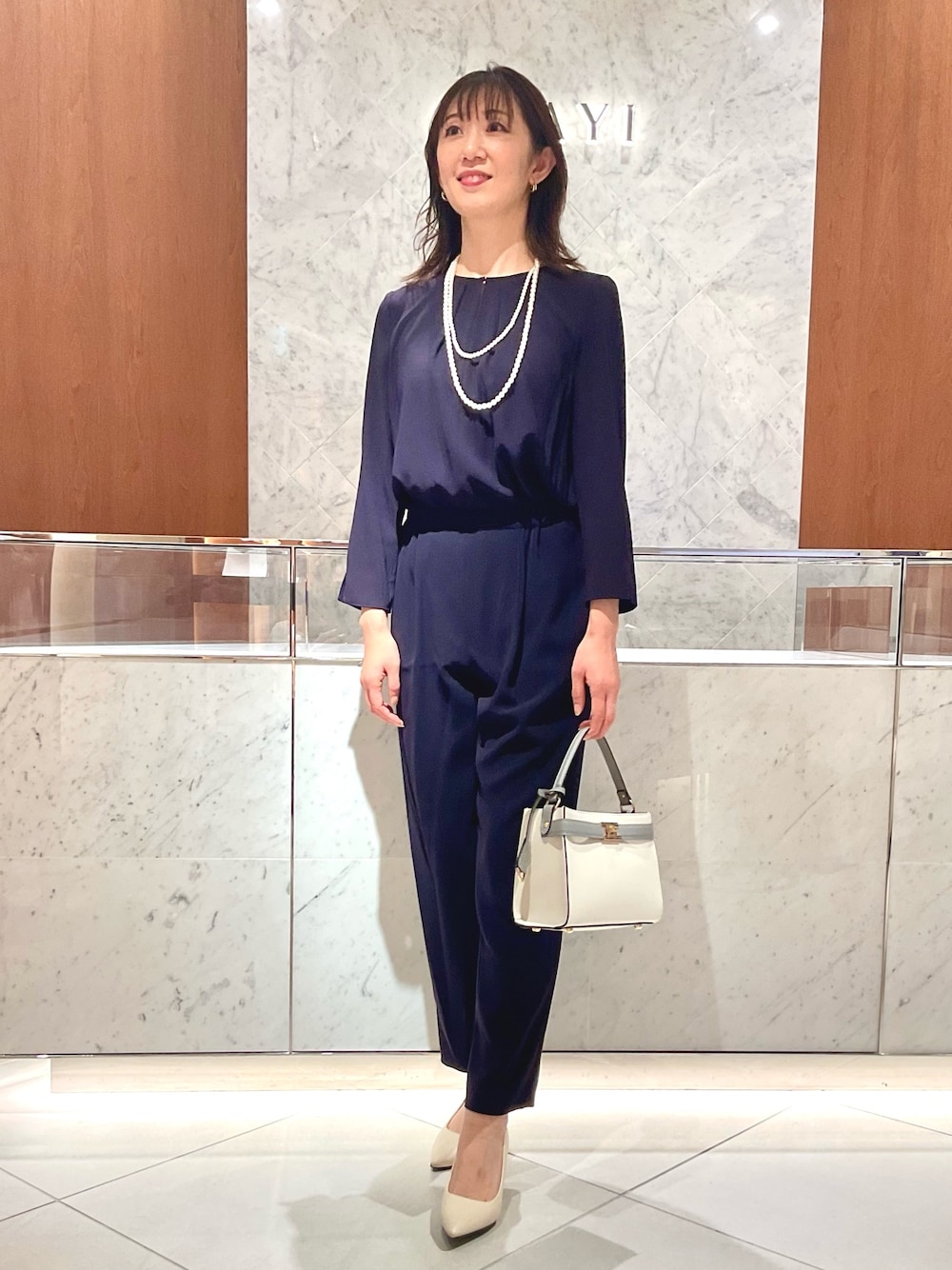 ブルー系のつなぎ/オールインワン、ホワイト系のハンドバッグ、ホワイト系のネックレスを着用したレディースの冬コーディネートの1枚目の写真