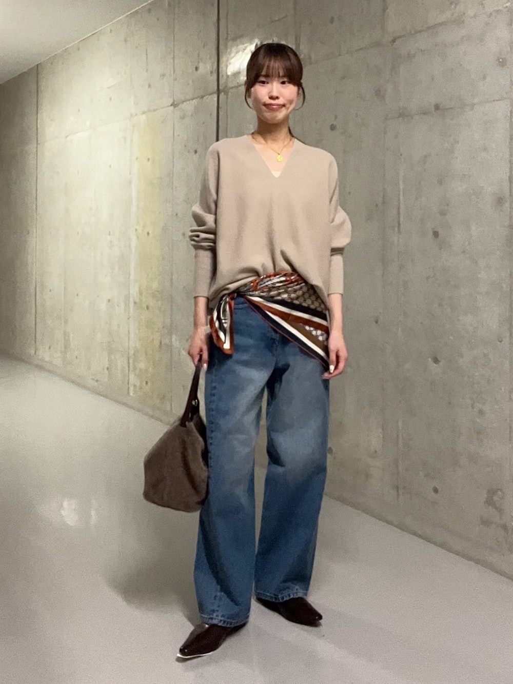 ブルー系のデニムパンツ、ブラウン系のハンドバッグ、ブラウン系のその他シューズを着用したレディースの秋コーディネートの1枚目の写真