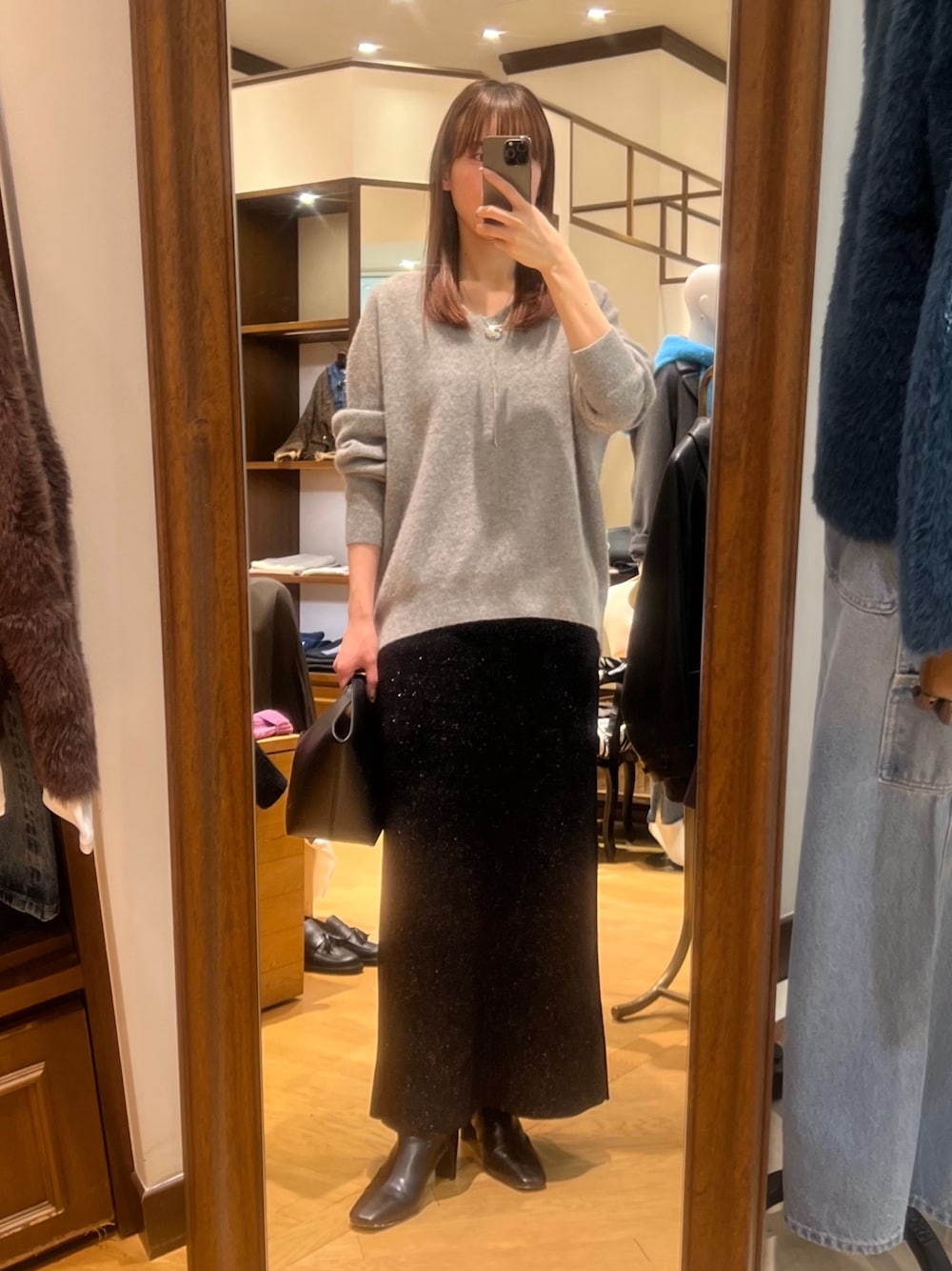 グレー系のニット/セーター、ブラック系のスカート、ブラック系のブーツを着用したレディースの冬コーディネートの1枚目の写真