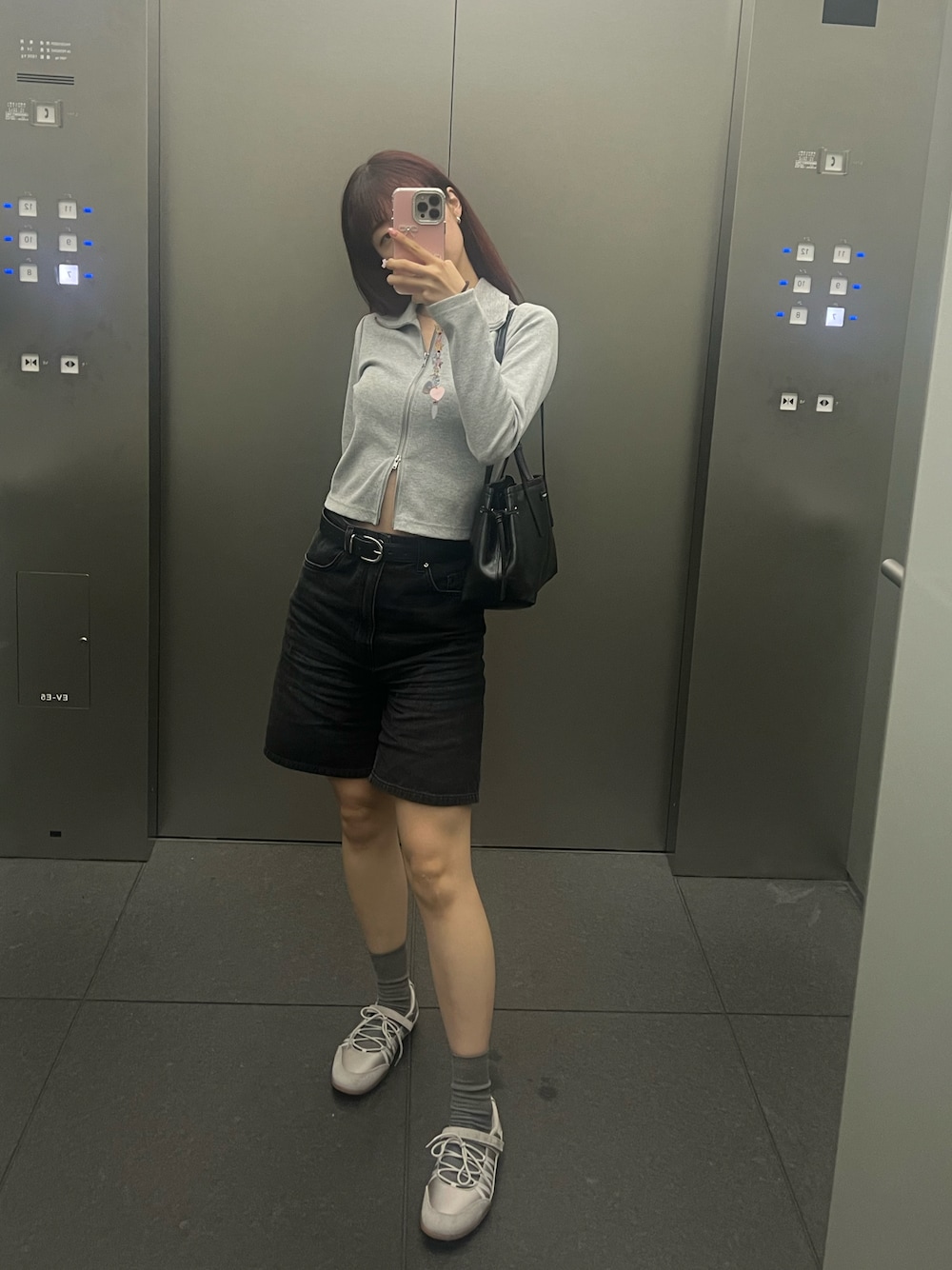 ブラック系のデニムパンツ、グレー系のTシャツ/カットソー、グレー系のスニーカーを着用したレディースの秋コーディネートの1枚目の写真