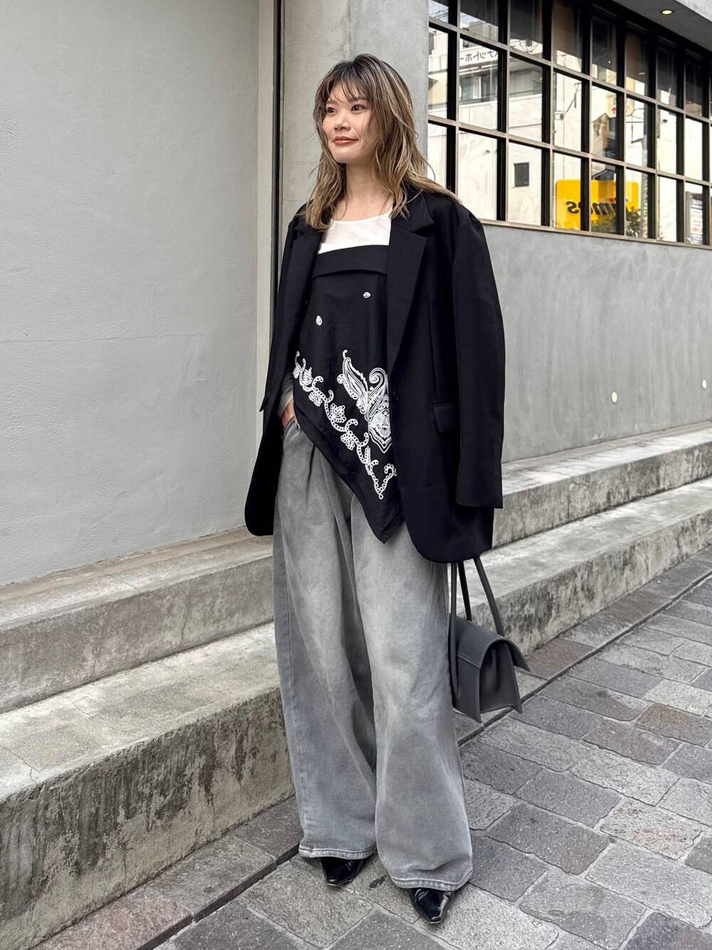 グレー系のデニムパンツ、ブラック系のテーラードジャケット、ホワイト系のTシャツ/カットソーを着用したレディースの春コーディネートの1枚目の写真