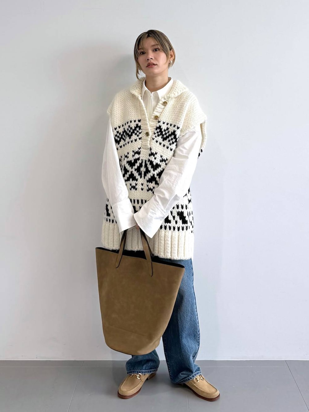 ブラウン系のトートバッグ、ブルー系のデニムパンツ、ホワイト系のシャツ/ブラウスを着用したレディースの秋コーディネートの1枚目の写真