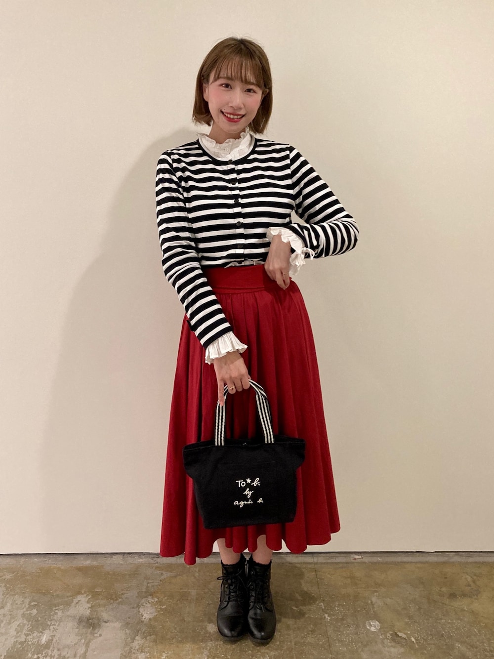 ブラック系のトートバッグ、レッド系のスカート、ブラック系のカーディガン/ボレロを着用したレディースの春コーディネートの1枚目の写真