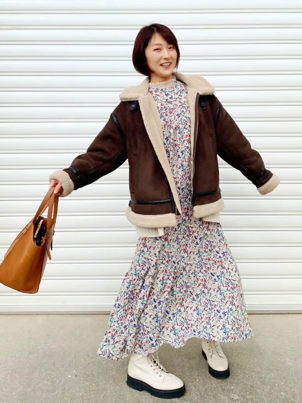 グリーン系のワンピース、ブラウン系のショルダーバッグ、ブラウン系のブルゾンを着用したレディースの冬コーディネートの2枚目の写真