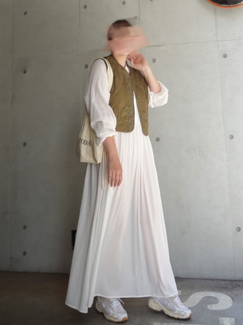 ホワイト系のシャツワンピース、グリーン系のベスト、ホワイト系のスニーカーを着用したレディースの秋コーディネートの1枚目の写真