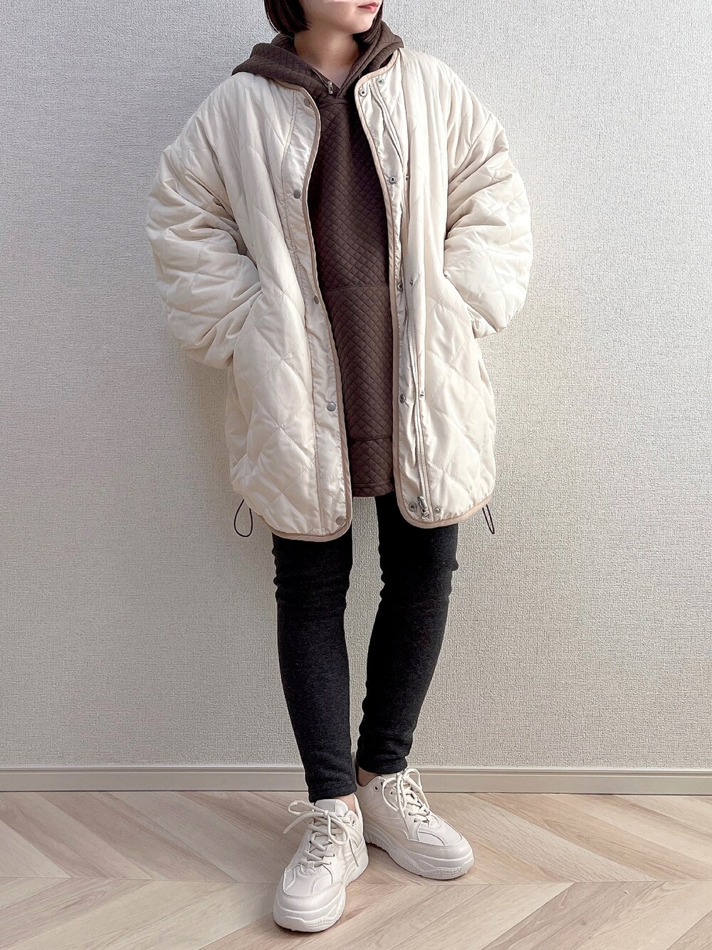ホワイト系のダウンジャケット/コート、ブラウン系のパーカー、ベージュ系のスニーカーを着用したレディースの秋コーディネートの1枚目の写真