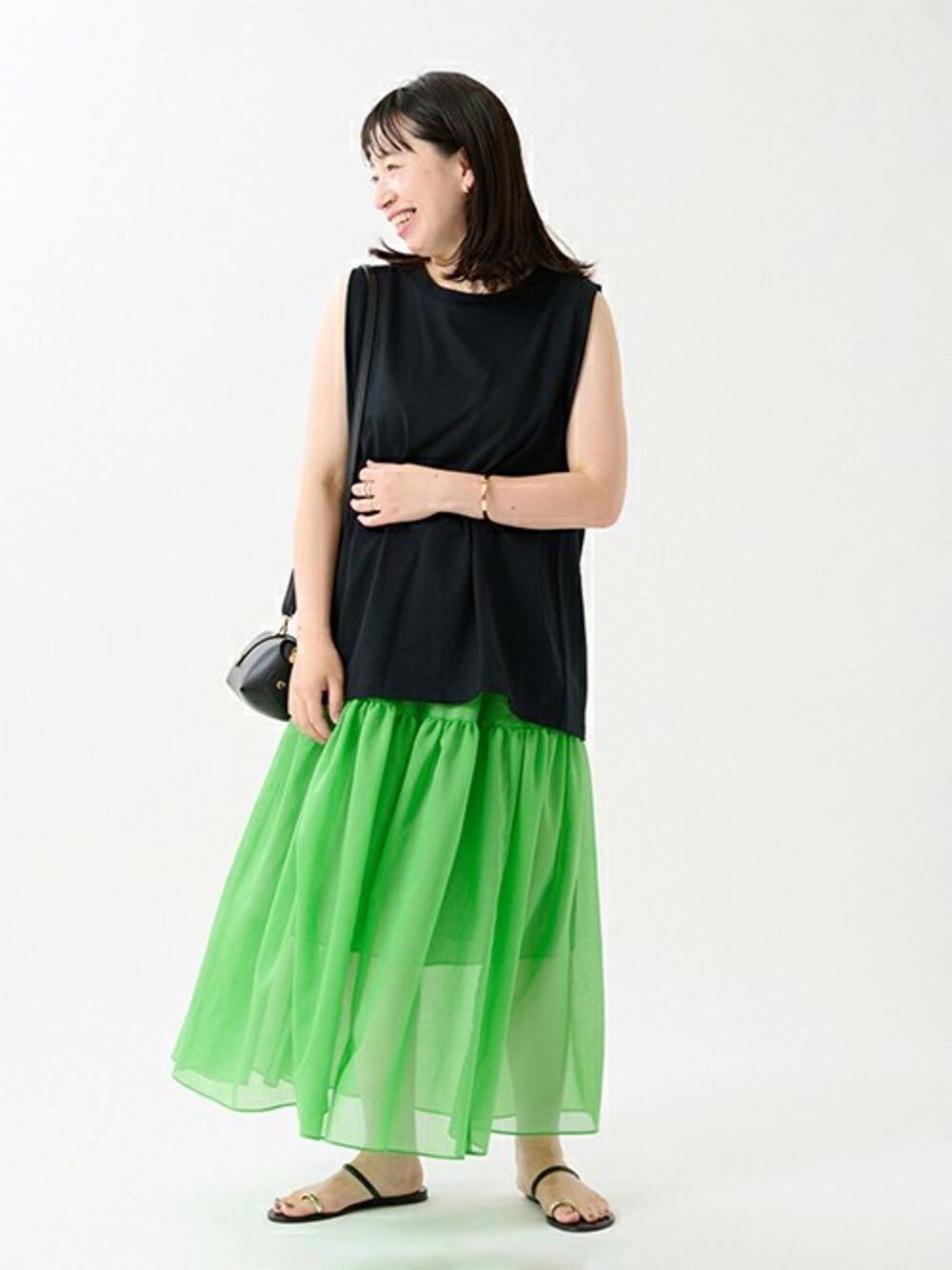 グリーン系のスカート、ブラック系のショルダーバッグ、ブラック系のTシャツ/カットソーを着用したレディースの夏コーディネートの1枚目の写真