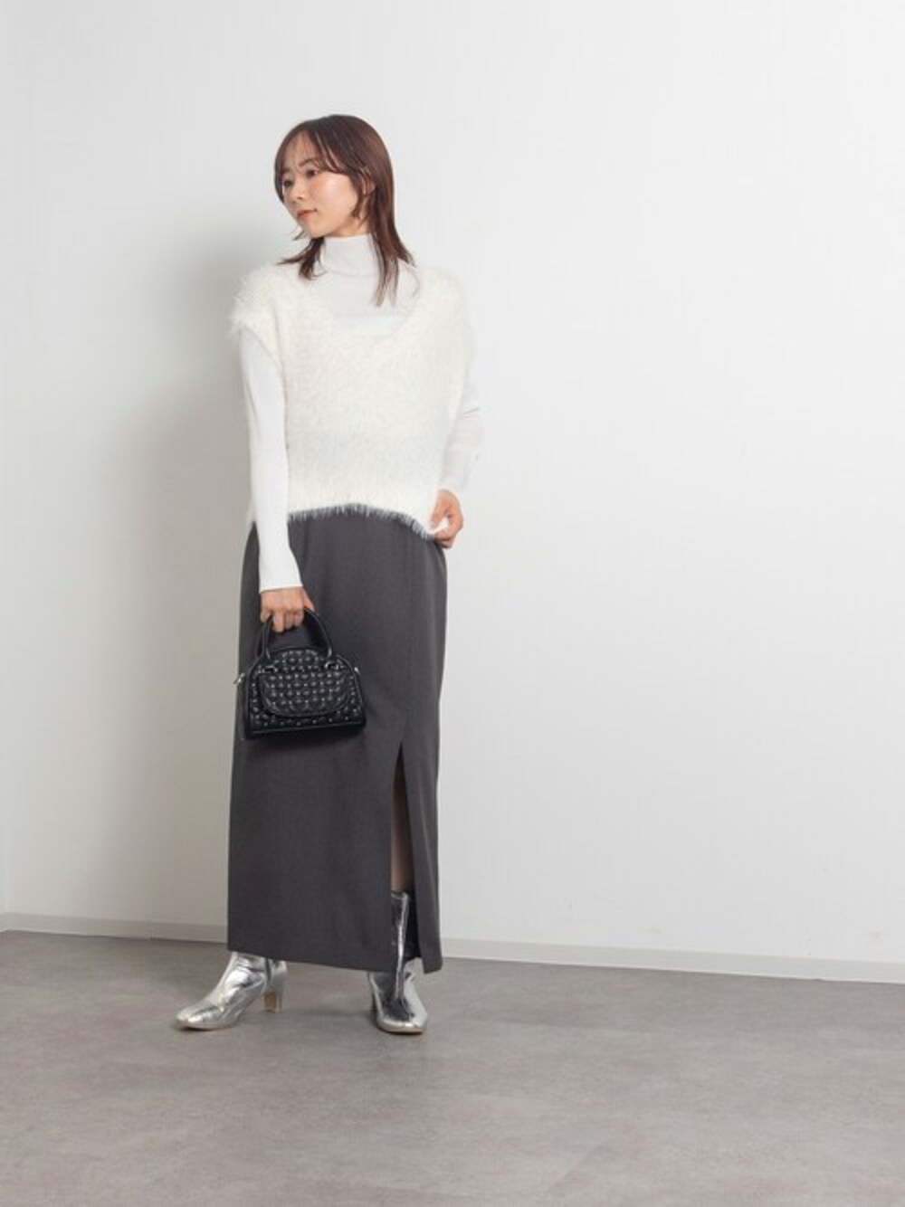 ホワイト系のベスト、グレー系のスカート、シルバー系のブーツを着用したレディースの夏コーディネートの1枚目の写真