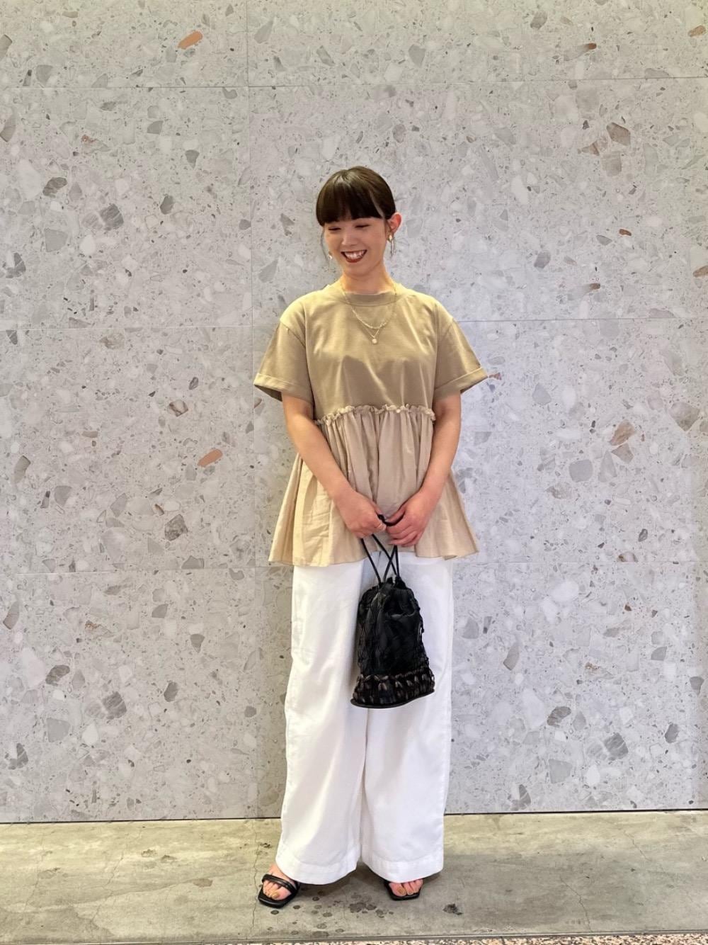 ブラック系のショルダーバッグ、ホワイト系のデニムパンツ、ベージュ系のTシャツ/カットソーを着用したレディースの夏コーディネートの1枚目の写真