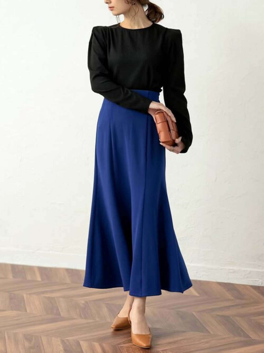 ブラック系のシャツ/ブラウス、ブルー系のスカート、イエロー系のパンプスを着用したレディースの春コーディネートの1枚目の写真