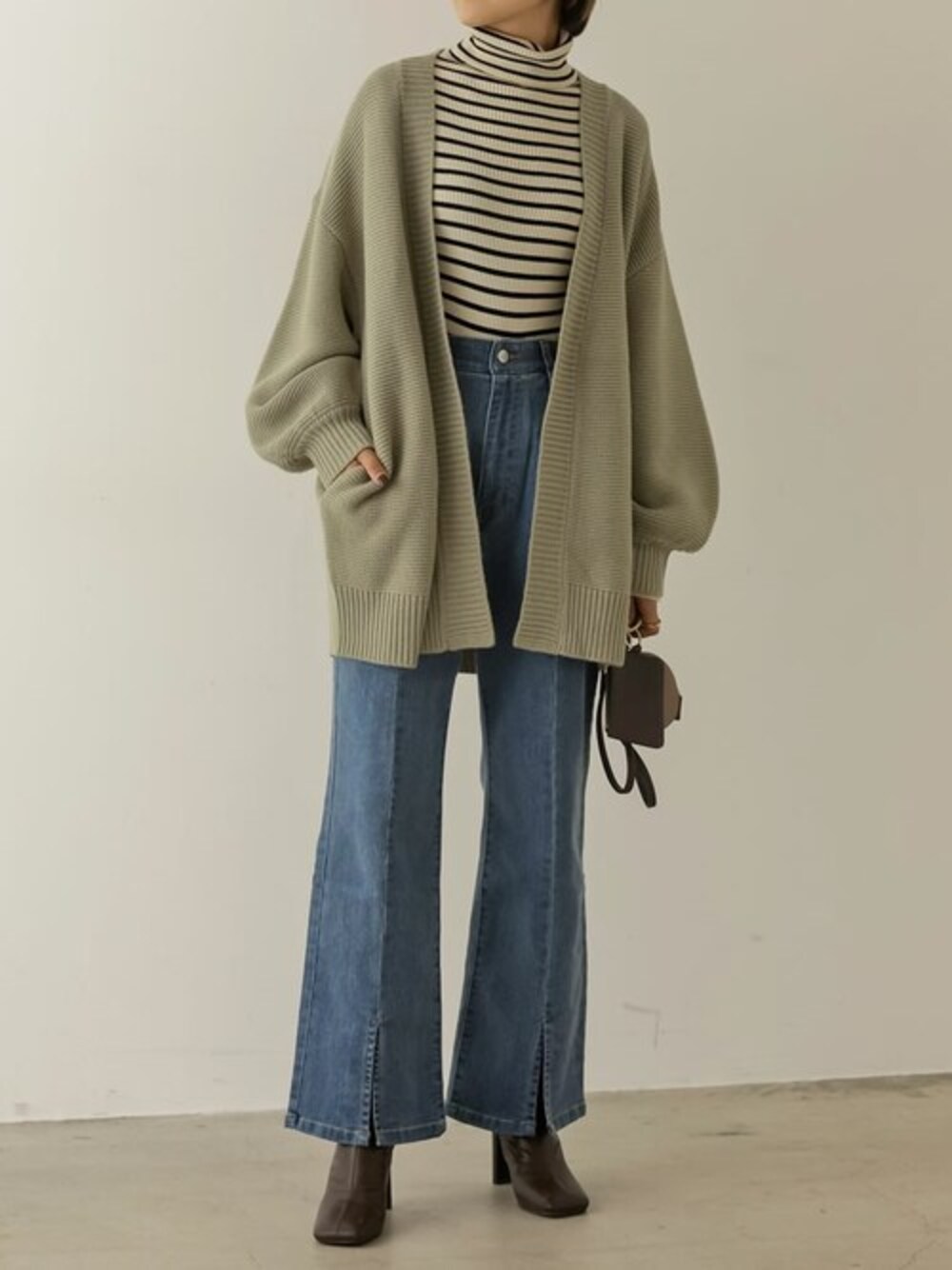 グリーン系のカーディガン/ボレロ、ホワイト系のニット/セーター、ブルー系のデニムパンツを着用したレディースの秋コーディネートの1枚目の写真