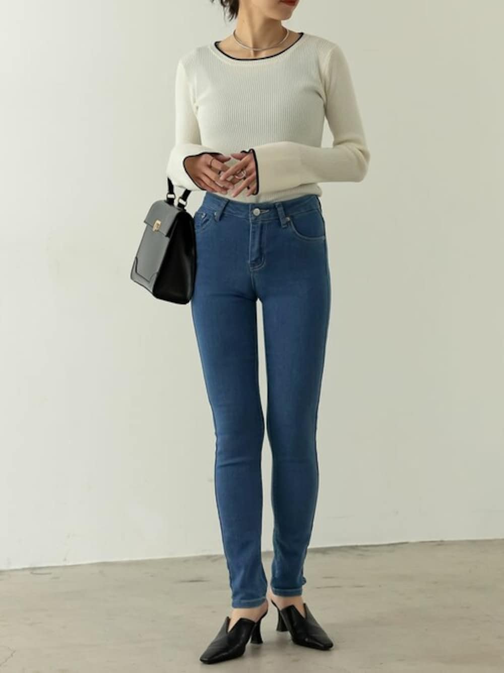 ホワイト系のニット/セーター、ブルー系のデニムパンツを着用したレディースの冬コーディネートの1枚目の写真