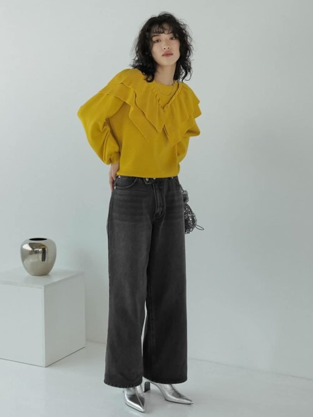 ブラック系のデニムパンツ、シルバー系のハンドバッグ、イエロー系のニット/セーターを着用したレディースの秋コーディネートの1枚目の写真