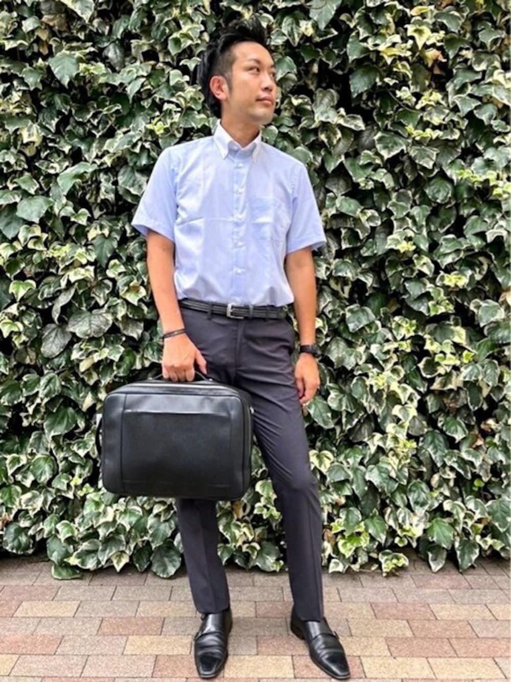 グレー系のスラックス、ブルー系のビジネスシャツ、ブラック系のビジネスバッグを着用したメンズの夏コーディネートの1枚目の写真