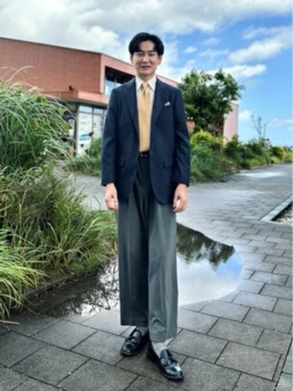 ブルー系のテーラードジャケット、グレー系のスラックスを着用したメンズの秋コーディネートの1枚目の写真
