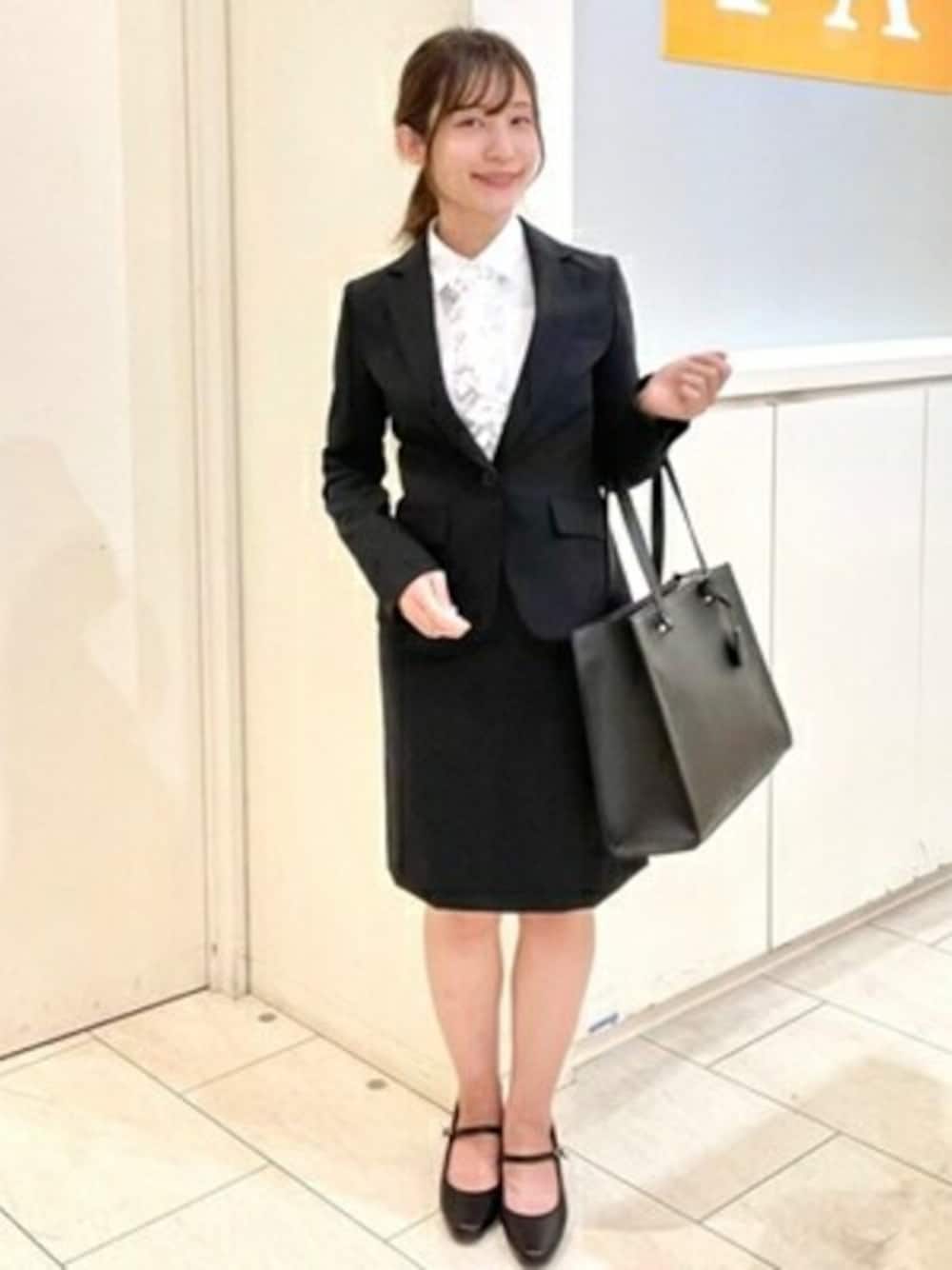 ブラック系のスーツジャケット、ホワイト系のビジネスシャツを着用したレディースの冬コーディネートの1枚目の写真