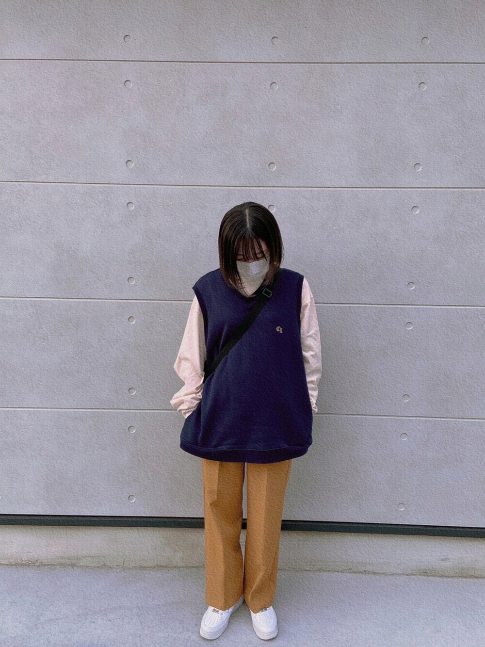 イエロー系のスラックス、ホワイト系のスニーカー、ブルー系のベストを着用したレディースの秋コーディネートの1枚目の写真