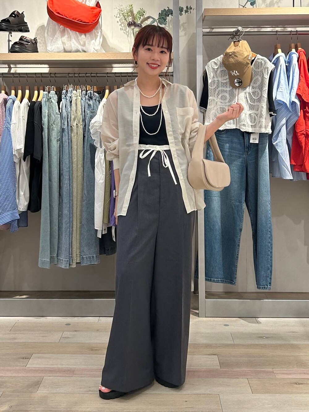 ベージュ系のハンドバッグ、ブラック系のサンダル、ホワイト系のシャツ/ブラウスを着用したレディースの夏コーディネートの1枚目の写真