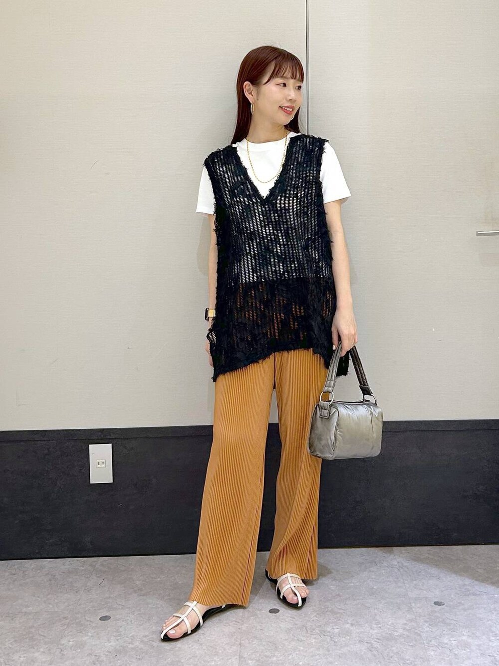 ブラック系のベスト、ホワイト系のTシャツ/カットソー、ホワイト系のサンダルを着用したレディースの春コーディネートの1枚目の写真