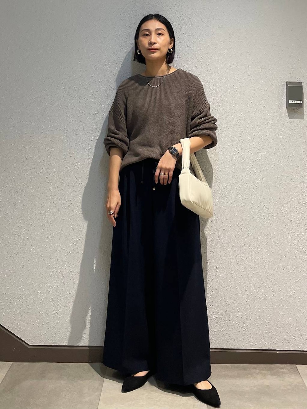 ブラック系のパンプス、ブルー系のその他パンツ、ブラウン系のニット/セーターを着用したレディースの春コーディネートの1枚目の写真