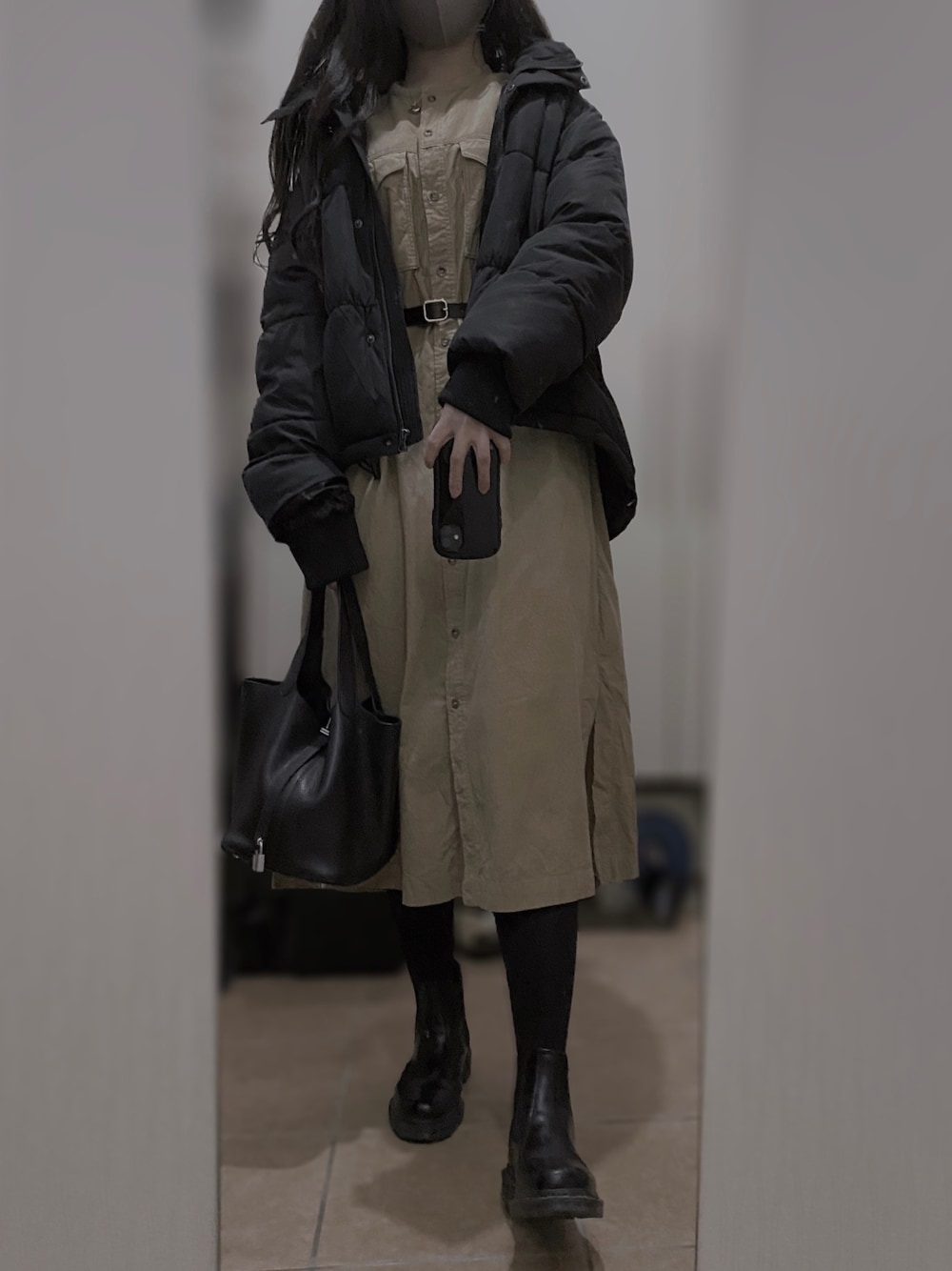 ブラック系のブーツ、ベージュ系のワンピース、ブラック系のダウンジャケット/コートを着用したレディースの冬コーディネートの1枚目の写真