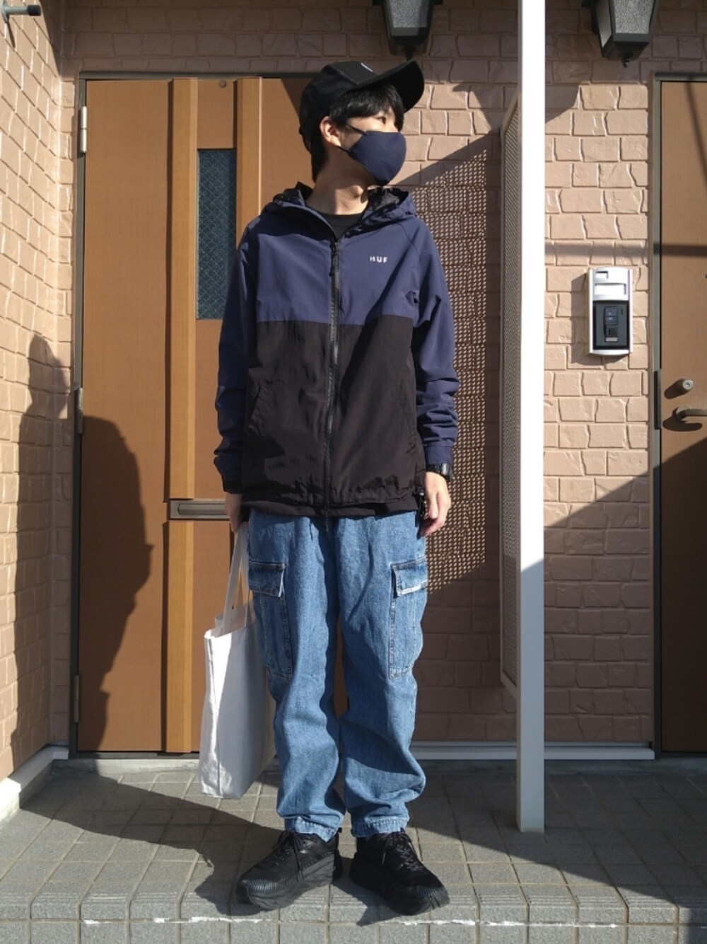 ブラック系のスニーカー、ブルー系のブルゾン、ブルー系のカーゴパンツを着用したメンズの秋コーディネートの1枚目の写真