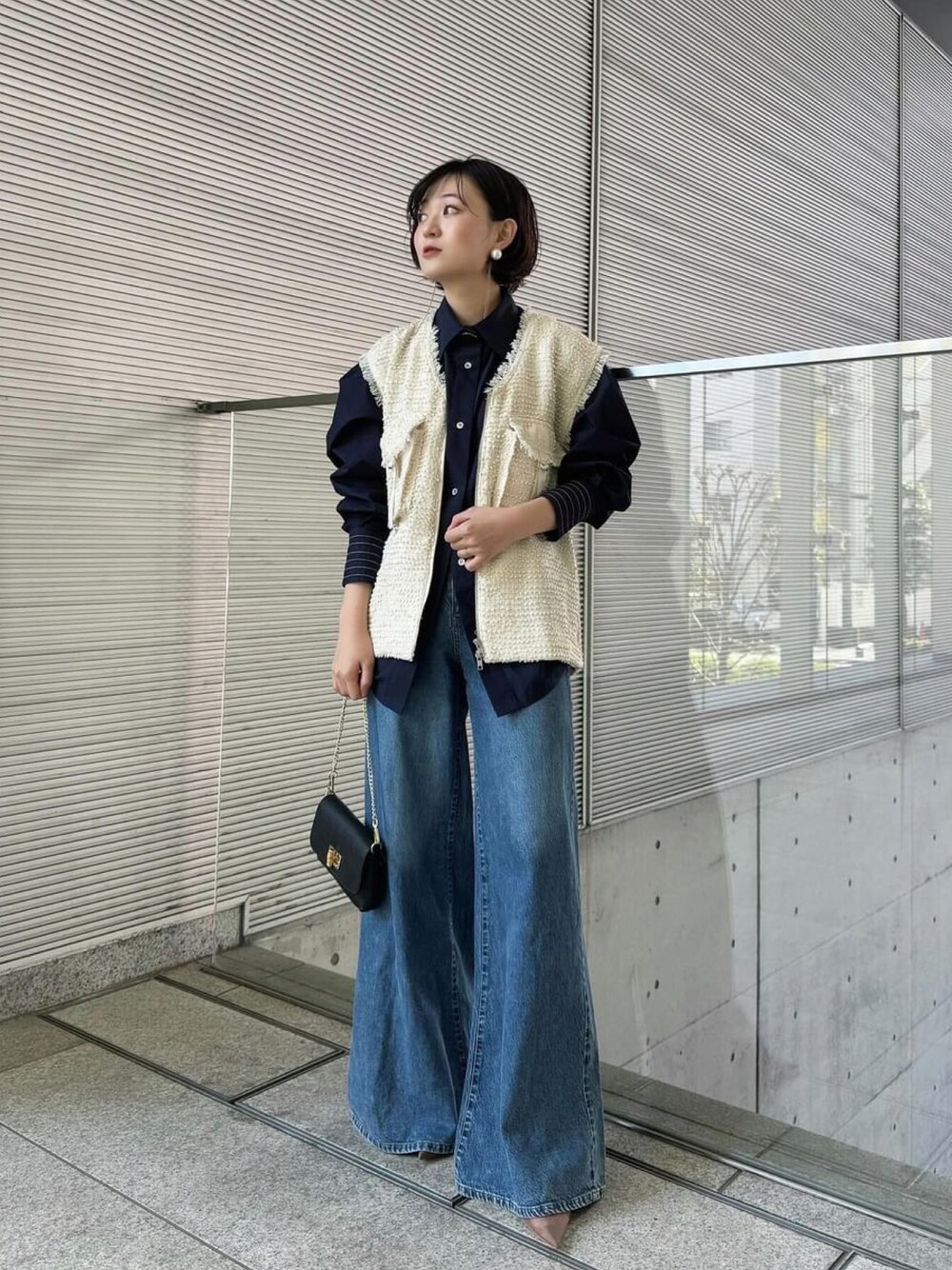 ホワイト系のベスト、ブルー系のシャツ/ブラウス、ブルー系のデニムパンツを着用したレディースの春コーディネートの1枚目の写真