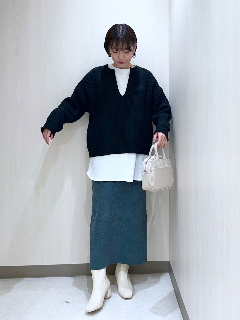 ブラック系のニット/セーター、ホワイト系のTシャツ/カットソー、グリーン系のスカートを着用したレディースの秋コーディネートの1枚目の写真