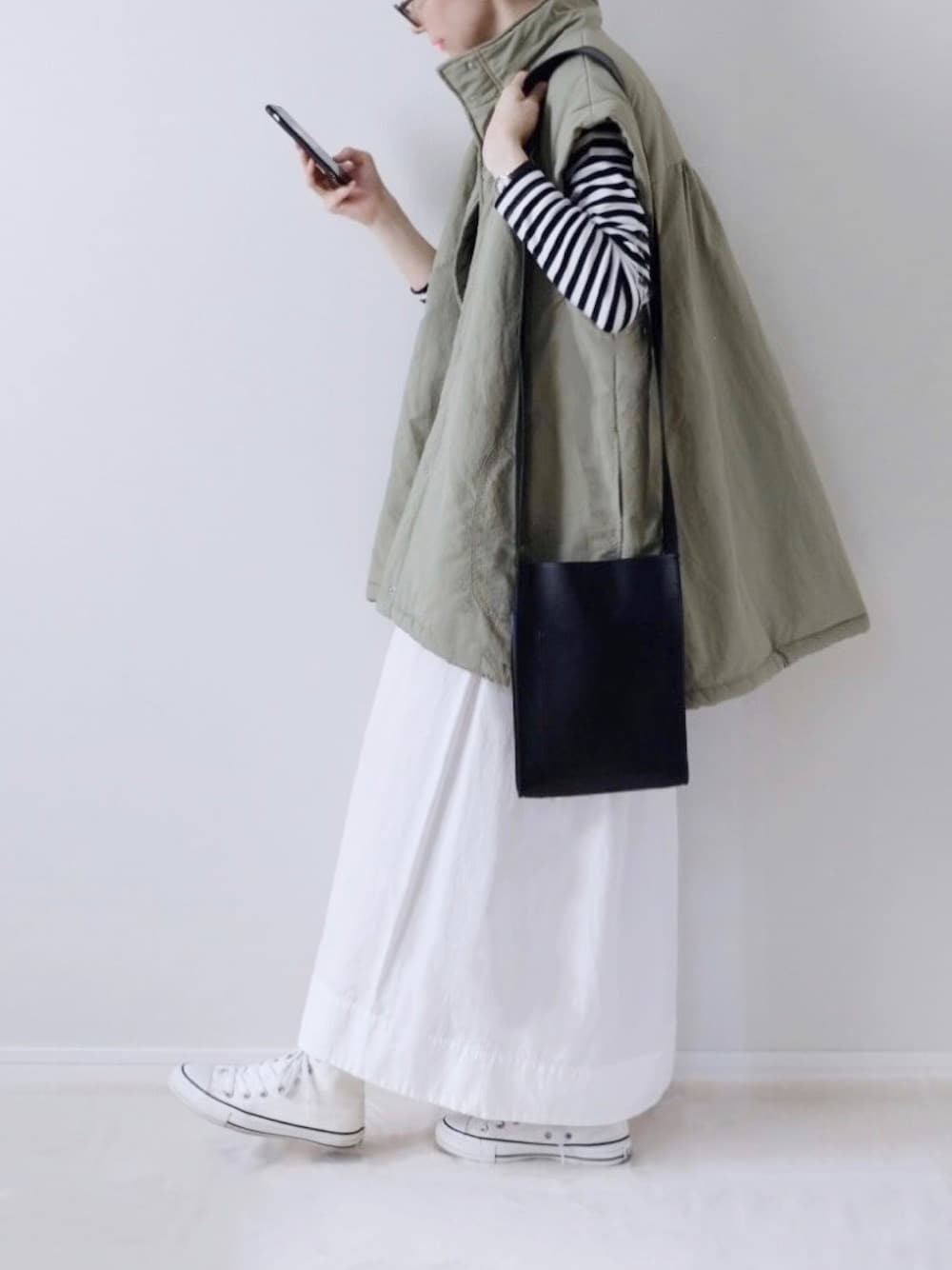 ブラック系のTシャツ/カットソー、ホワイト系のスカート、ホワイト系のスニーカーを着用したレディースの秋コーディネートの1枚目の写真