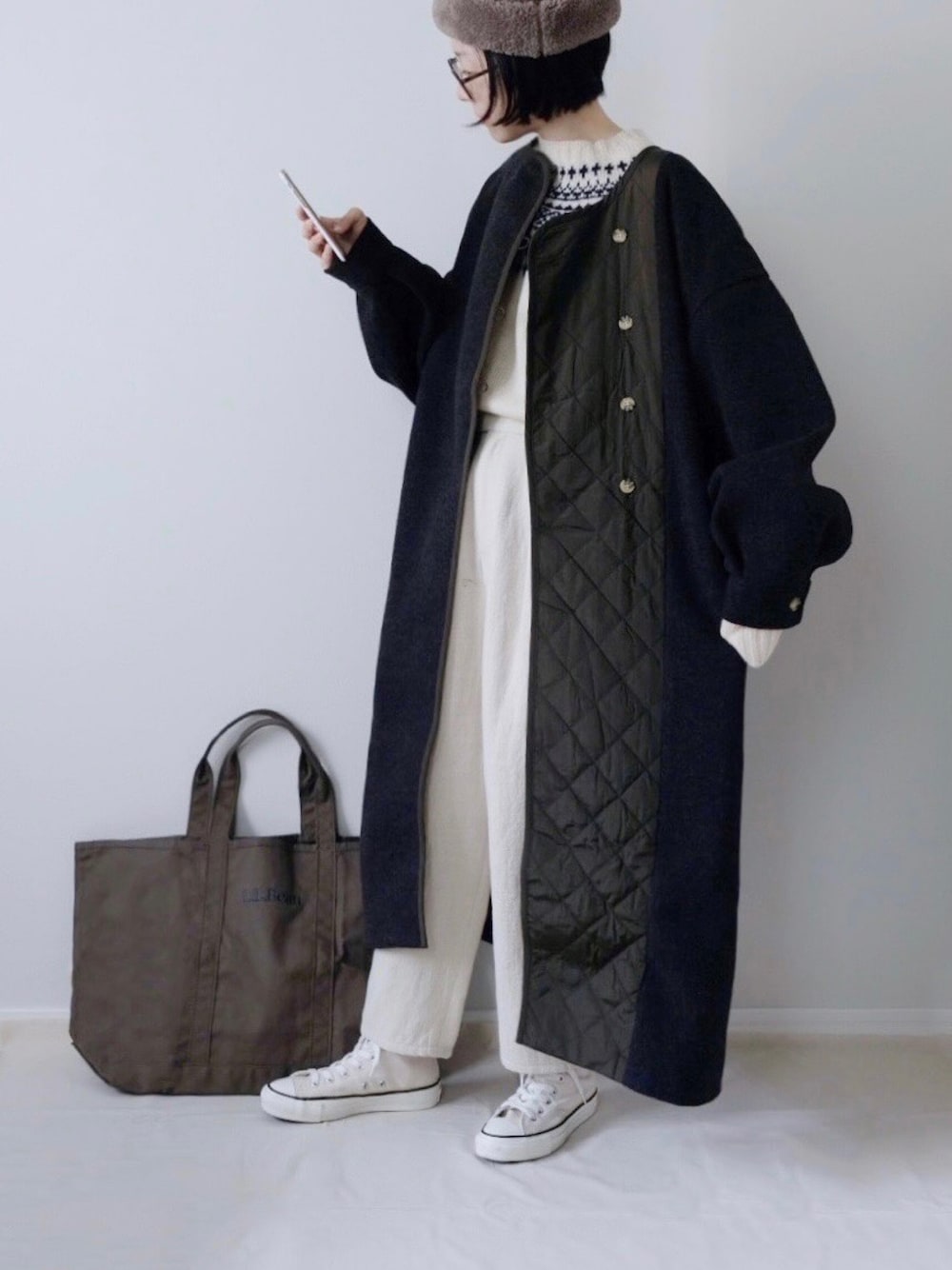 ホワイト系のスニーカー、ブラウン系のハットを着用したレディースの冬コーディネートの1枚目の写真