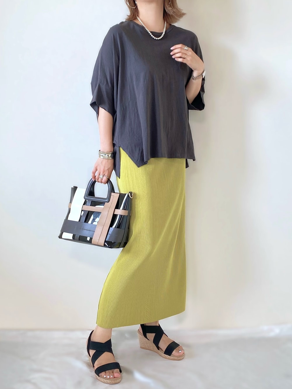 グレー系のTシャツ/カットソー、グリーン系のスカート、ブラック系のバッグを着用したレディースの夏コーディネートの1枚目の写真