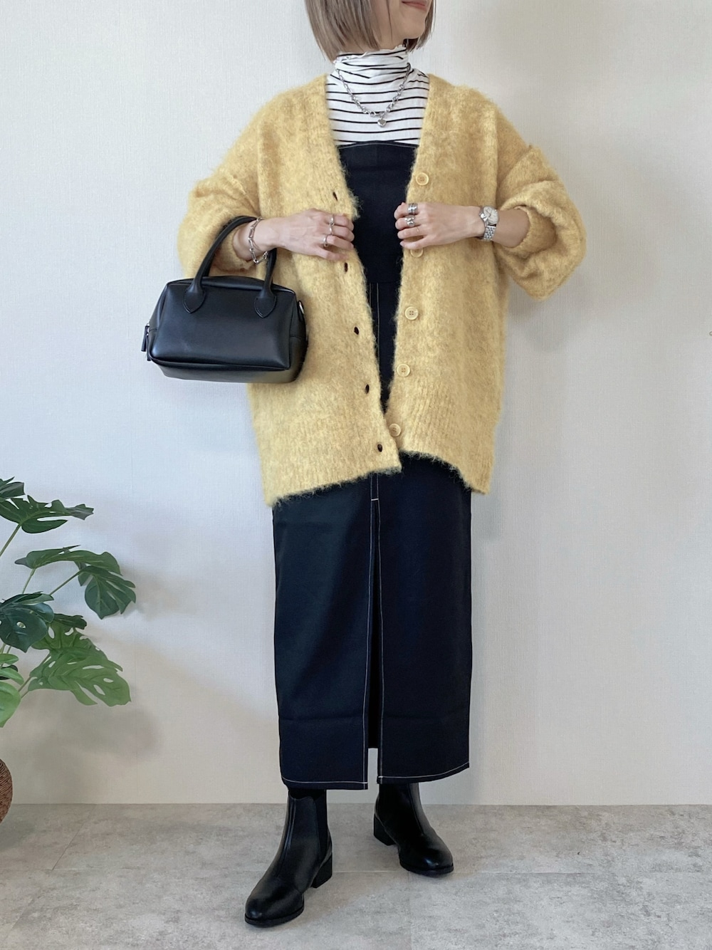 ブラック系のワンピース、ブラック系のブーツ、ブラック系のバッグを着用したレディースの冬コーディネートの1枚目の写真