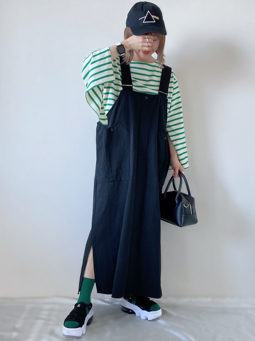 グリーン系のTシャツ/カットソー、ブラック系のスカート、ブラック系のバッグを着用したレディースの春コーディネートの1枚目の写真