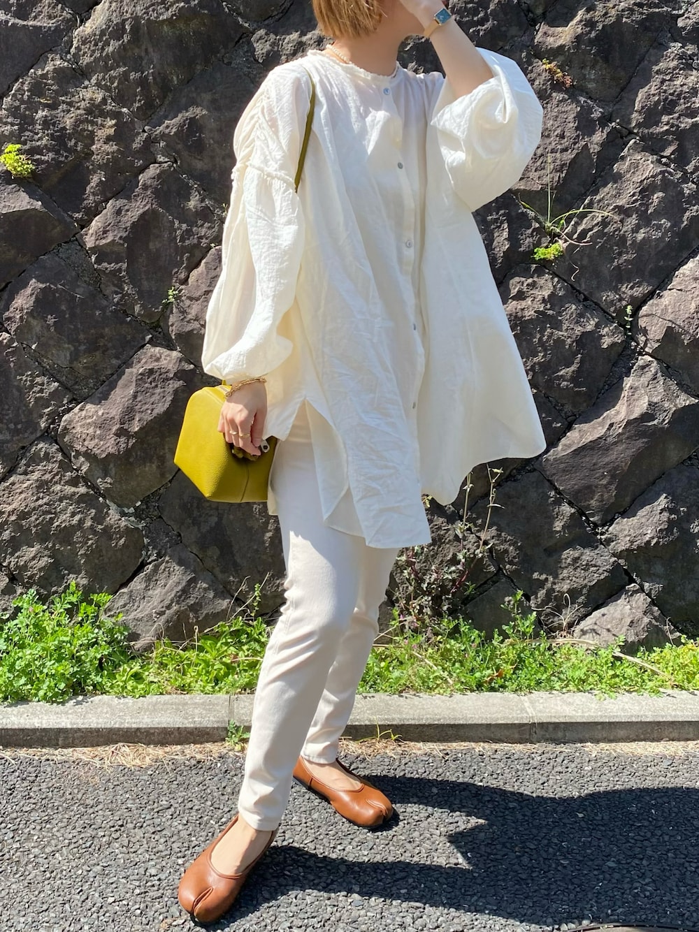 ブラウン系のパンプス、グリーン系のボストンバッグ、ホワイト系のシャツ/ブラウスを着用したレディースの春コーディネートの1枚目の写真