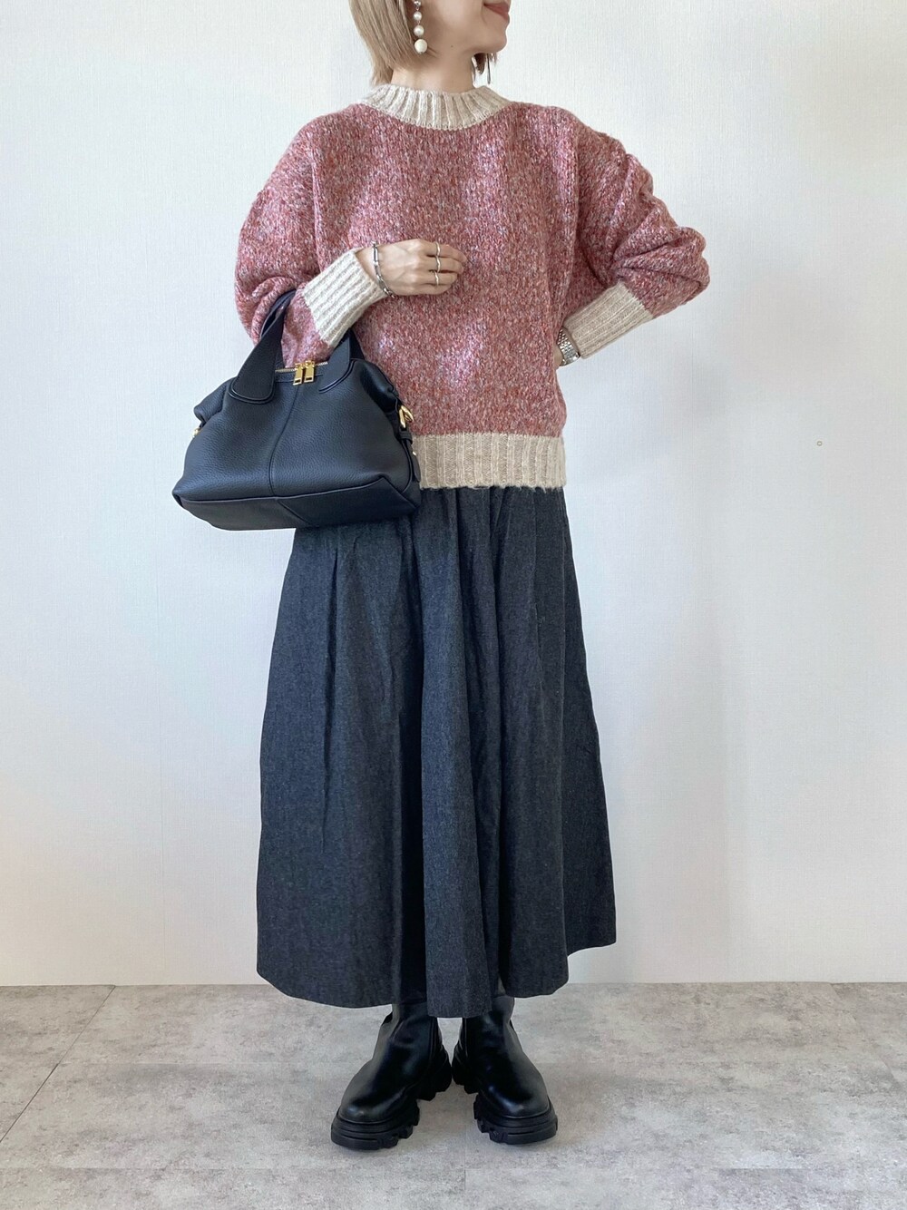 ピンク系のニット/セーター、ブラック系のバッグ、ブラック系のスカートを着用したレディースの秋コーディネートの1枚目の写真