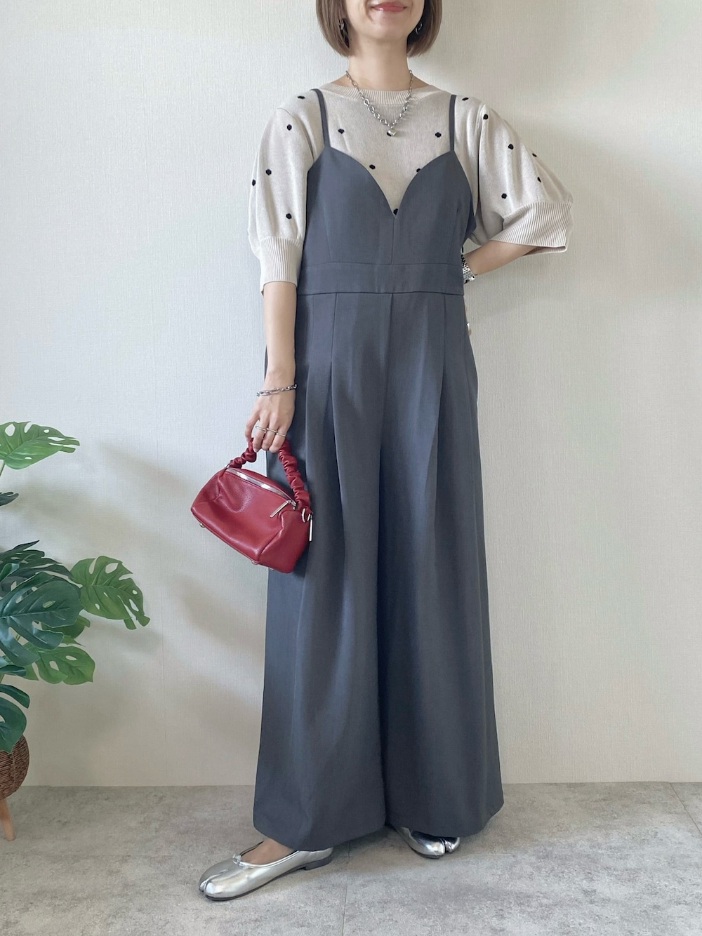 レッド系のボストンバッグ、グレー系のサロペット/オーバーオール、ベージュ系のニット/セーターを着用したレディースの夏コーディネートの1枚目の写真