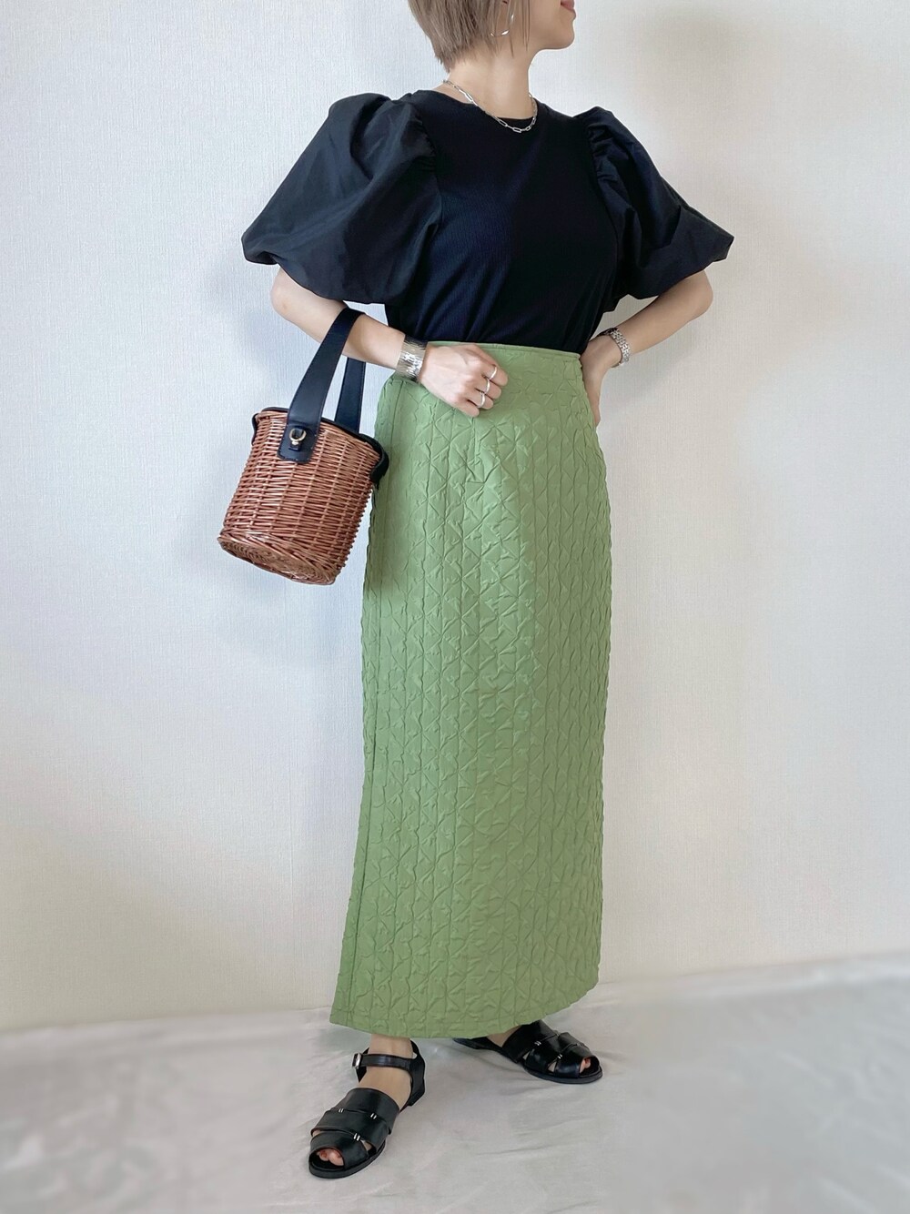 グリーン系のスカート、ブラック系のトップス、ブラック系のバッグを着用したレディースの夏コーディネートの1枚目の写真
