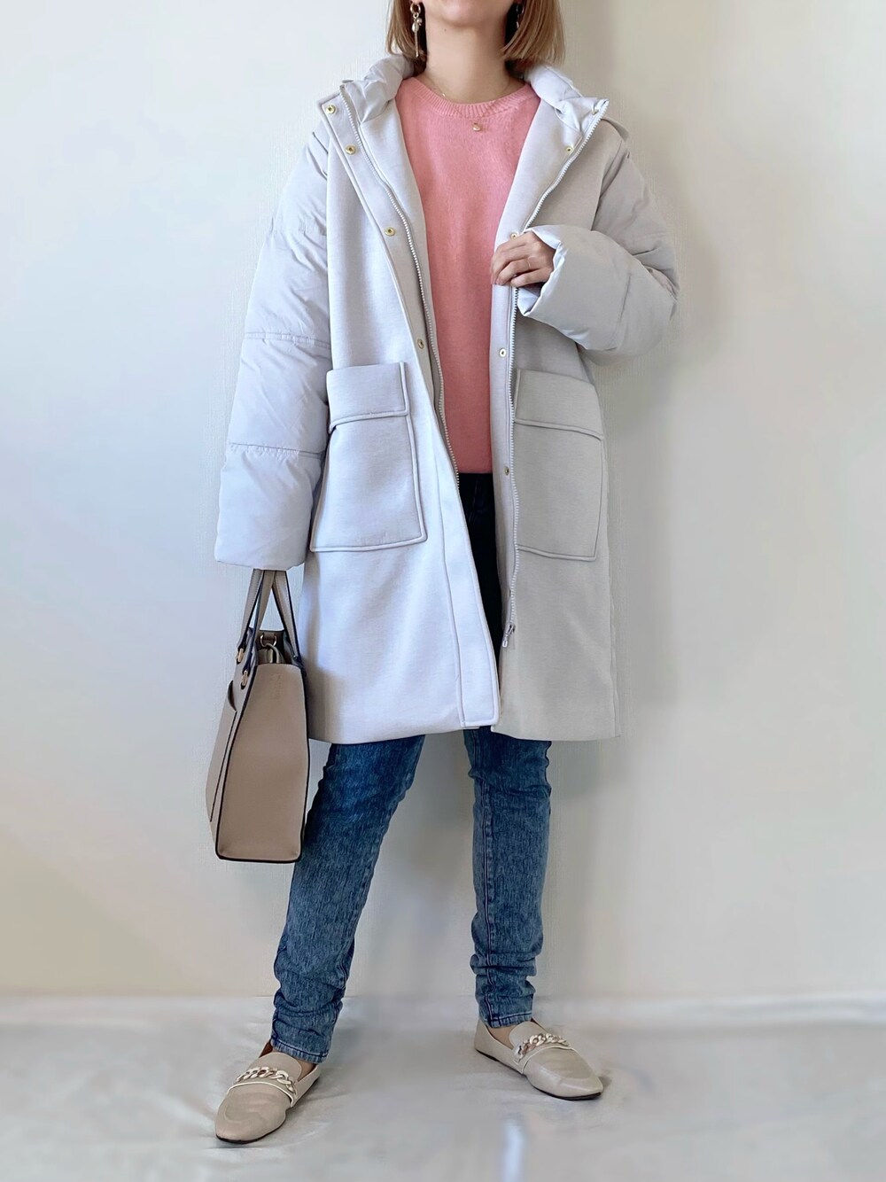 ピンク系のニット/セーター、グレー系のダウンジャケット/コート、ベージュ系のバッグを着用したレディースの冬コーディネートの1枚目の写真