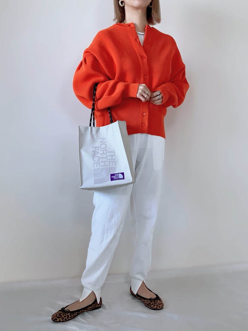 オレンジ系のカーディガン/ボレロ、ホワイト系のその他パンツ、ベージュ系のトートバッグを着用したレディースの春コーディネートの1枚目の写真