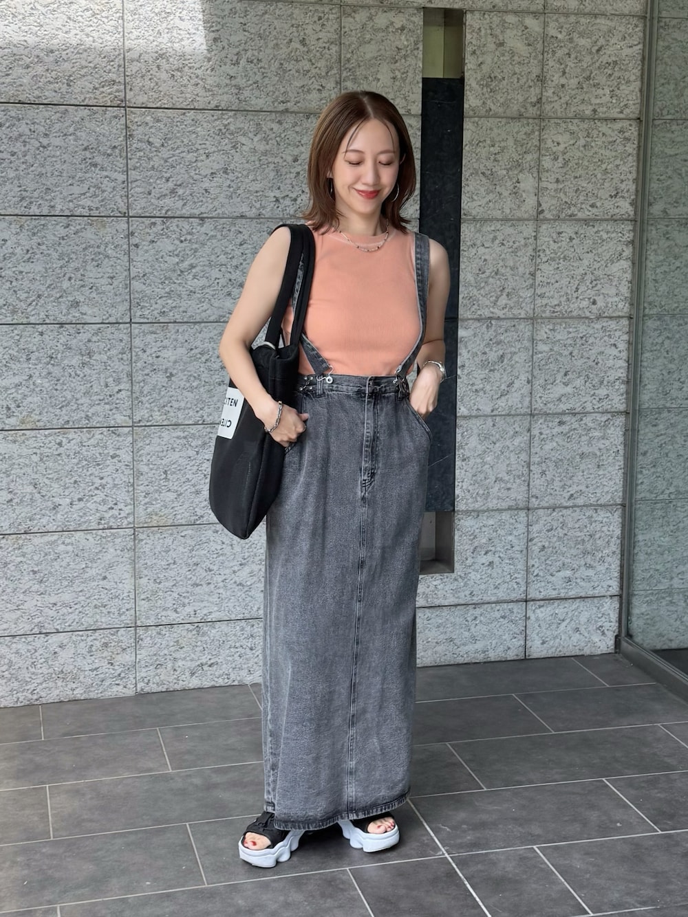 ブラック系のサンダル、ピンク系のTシャツ/カットソー、ブラック系のジャンパースカートを着用したレディースの夏コーディネートの1枚目の写真