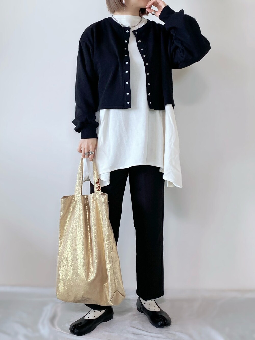ブラック系のカーディガン/ボレロ、ホワイト系のTシャツ/カットソー、ブラック系のスラックスを着用したレディースの冬コーディネートの1枚目の写真
