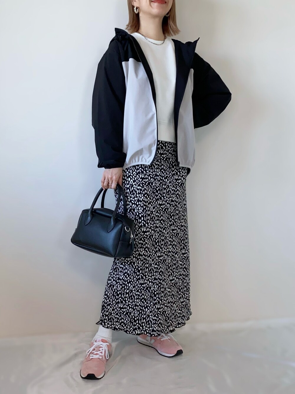 ブラック系のバッグ、ブラック系のスカート、ベージュ系のマウンテンパーカーを着用したレディースの春コーディネートの1枚目の写真