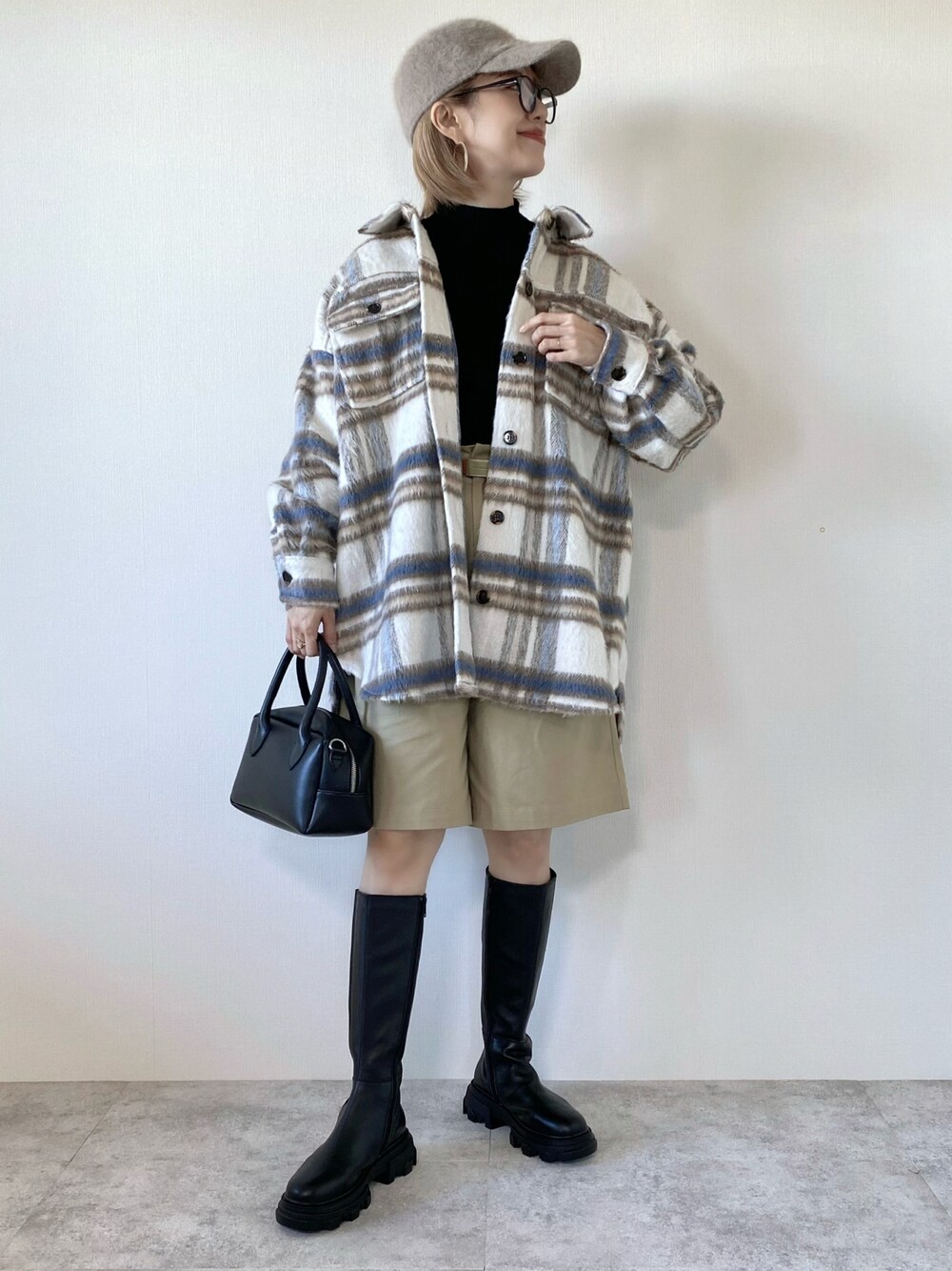 ホワイト系のブルゾン、ブラック系のニット/セーター、ブラック系のバッグを着用したレディースの秋コーディネートの1枚目の写真