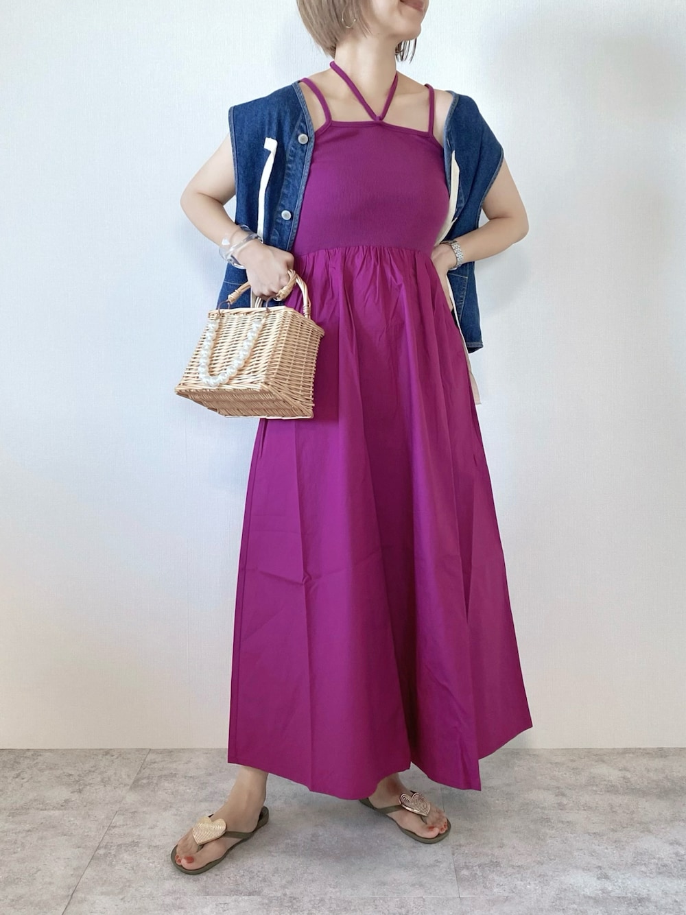 ピンク系のワンピース、ベージュ系のかごバッグ、ブルー系のベストを着用したレディースの夏コーディネートの1枚目の写真