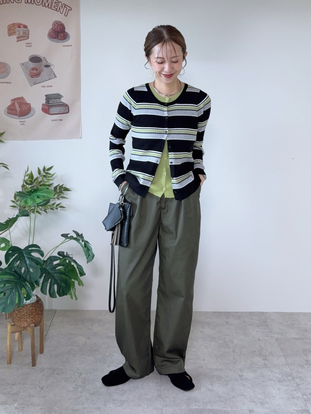 グリーン系のチノパンツ、ブラック系のパンプス、ブラック系のカーディガン/ボレロを着用したレディースの秋コーディネートの1枚目の写真