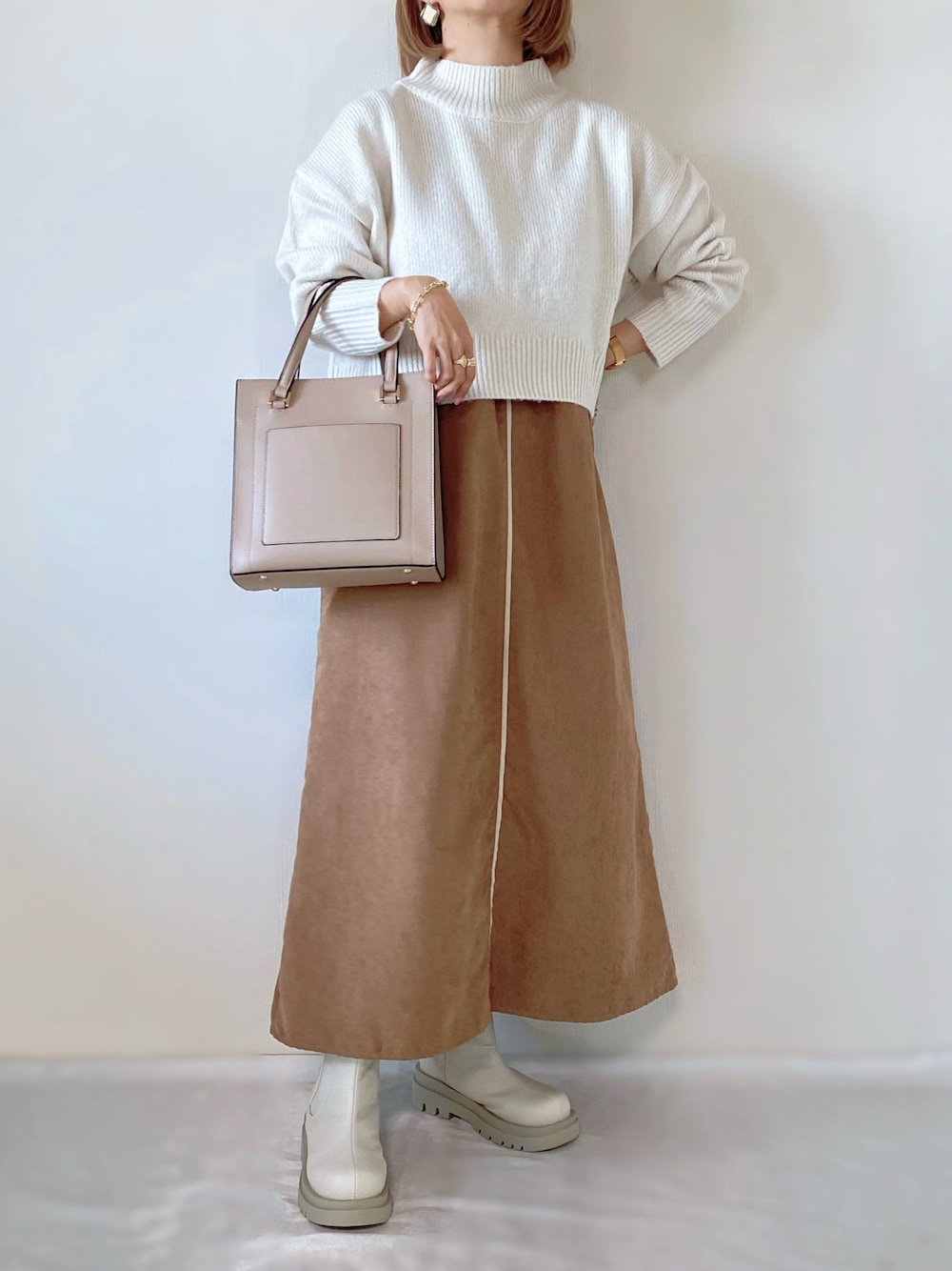 ホワイト系のニット/セーター、ブラウン系のワンピース、ホワイト系のブーツを着用したレディースの秋コーディネートの1枚目の写真