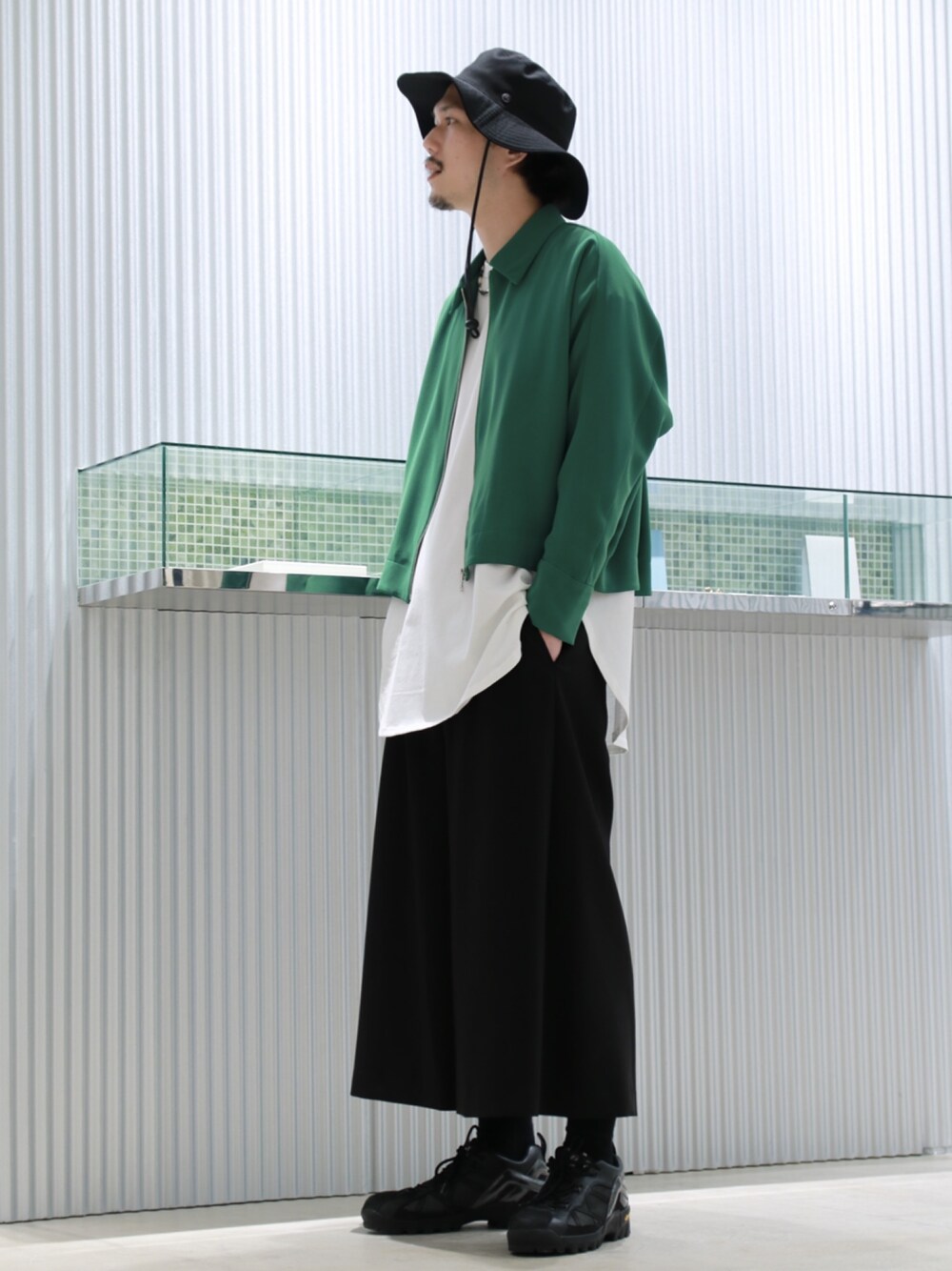 ブラック系のブルゾン、ホワイト系のTシャツ/カットソー、ブラック系のスラックスを着用したメンズの春コーディネートの2枚目の写真
