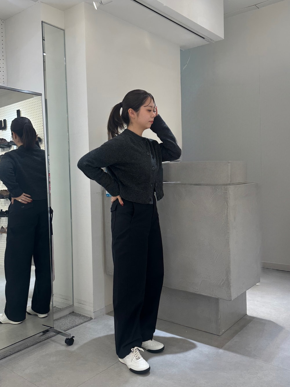 ホワイト系のスニーカー、グレー系のカーディガン/ボレロ、ブラック系のパンツを着用したレディースの秋コーディネートの1枚目の写真